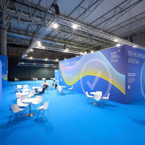 Vista frontal de la zona Speakers Management en EULAR 2025, con paneles azules y señalización clara para ponentes.