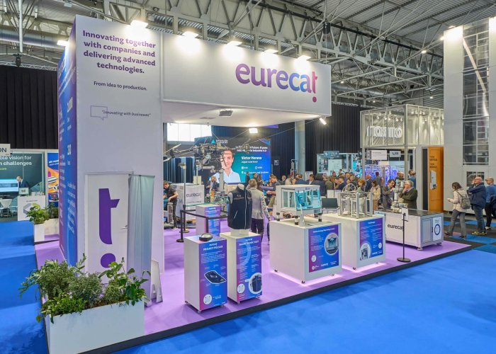 Vista frontal del stand de DELTECO en Advanced Factories 2025, con maquinaria en funcionamiento y zona de reuniones.