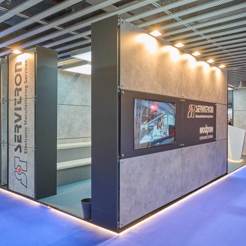 Stand Servitron de vista exterior izquierda donde queda vista su logo en la parte izquieda de la imagen y una pantalla embedida en la derecha